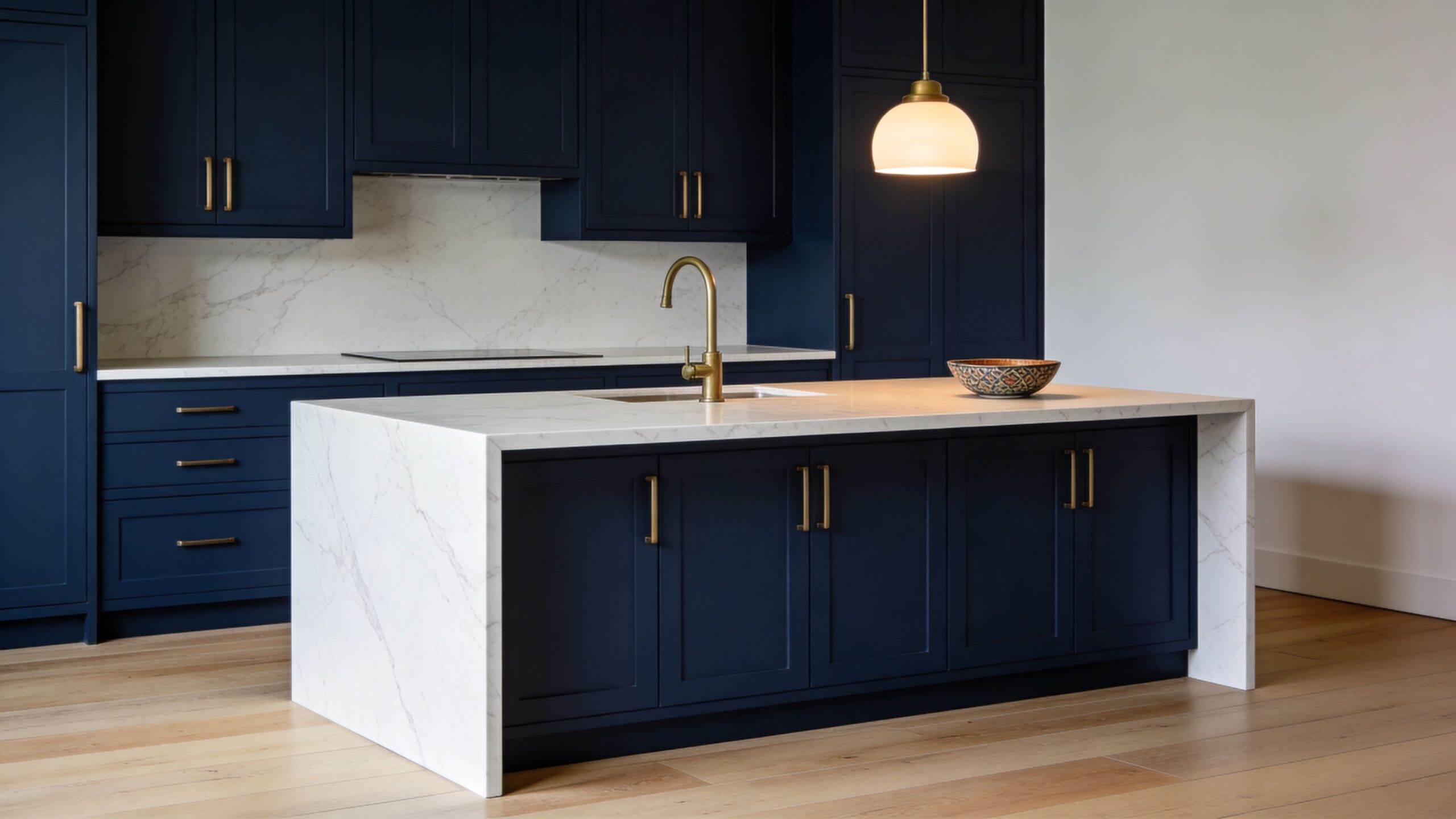 A modern kitchen with deep navy cabinets, white marble countertops, and a waterfall island design.