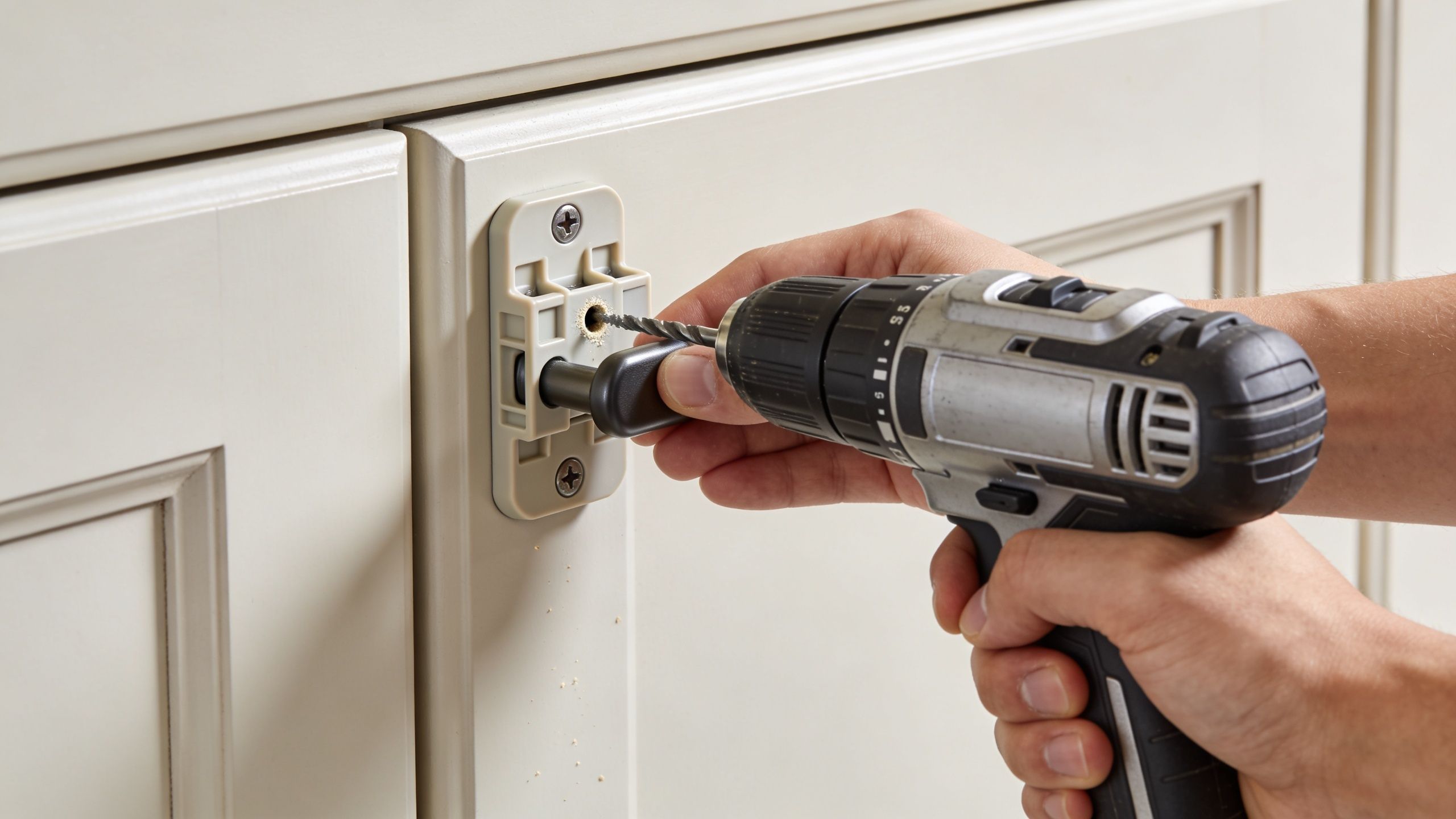 A person uses a power drill to install a plastic template for mounting new cabinet hardware.