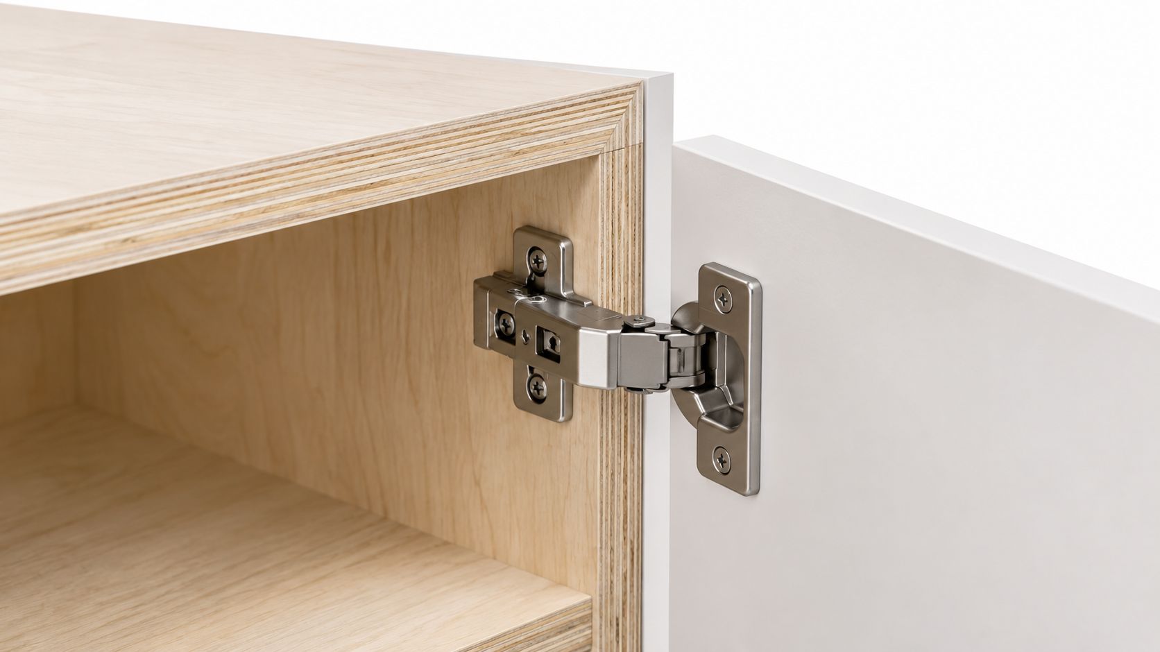 A close-up view of a modern European style hinge attached to a wooden kitchen cabinet door.